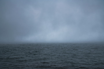Beautiful foggy landscape. Huge clouds with fog on the lake.