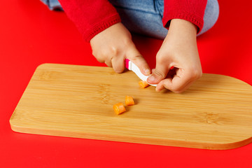 Little child hands cutting baby carrots on table