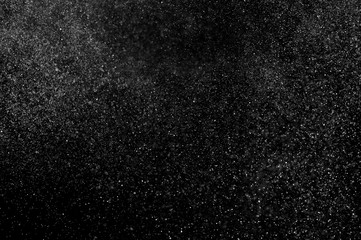 Abstract splashes of water on black background. Freeze motion of white particles. Rain, snow overlay texture.