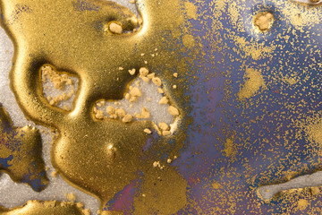 Piles of gold sequins on blue liquid ink background. Abstract pattern.