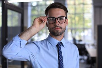 Fototapeta premium Young handsome businessman smiling in an office environment