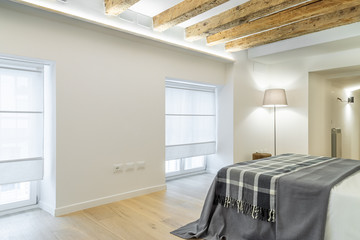 Bedroom in nordic style with white walls, wooden ceilings and exposed beams