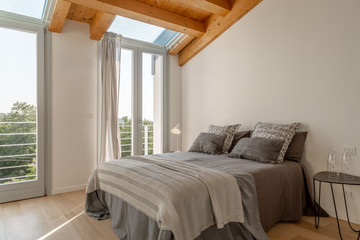 Bedroom in nordic style with white walls, wooden ceilings and exposed beams