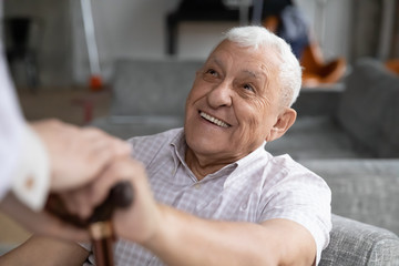 Head shot smiling old male pensioner involved in rehabilitation procedure with caring young...
