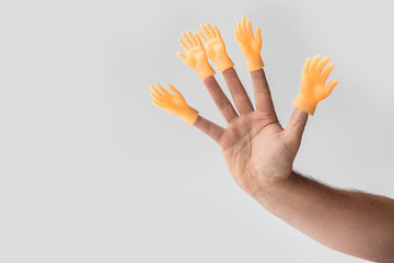 Hand on a white background on her fingers is wearing a toy in the shape of a hand. Concept. No...