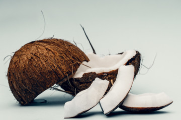 Parts of coconut on a colored background. Close up. Fresh ripe coconut broken into pieces.