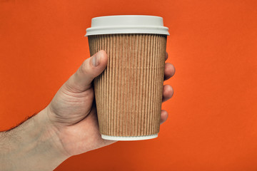 Paper cup in hand on a colored background. Eco-friendly materials in a coffee shop, biodegradable disposable tableware. Close up