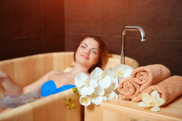 Obraz na płótnie Canvas A young girl enjoys an eco-friendly wooden Jacuzzi bath