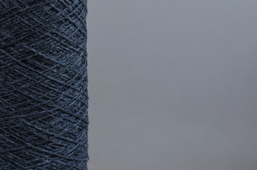 cone of gray wool yarn on light gray background. copy space