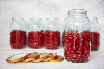 Not closed glass jars with cherries, prepared for canning with tin screw lids