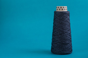 cone of gray wool yarn on turquoise background. copy space