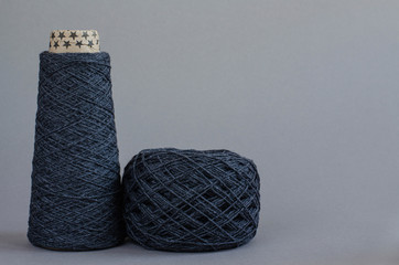 cone and ball of gray wool yarn on gray background. copy space