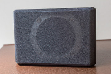 Front view of a grey loudspeaker on top of a leather table.