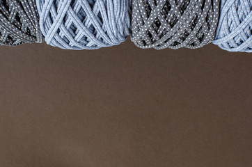 t-shirt yarn balls light gray color and dark gray with dots on brown background. Top view, copy space. Handmade craft recycle eco concept