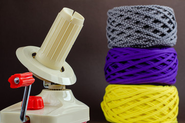 hand plastic wool winder, yellow, purple, gray yarn balls, brown background. Knitting, crochet,...