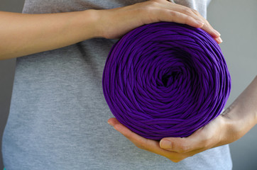female hands holding big purple t-shirt yarn ball. Handmade, craft, recycle, eco concept