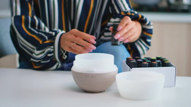 Close up of woman adding essential oils into diffuser. Aroma health essence, welness aromatherapy home spa fragrance tranquil theraphy, therapeutic steam, mental health treatment