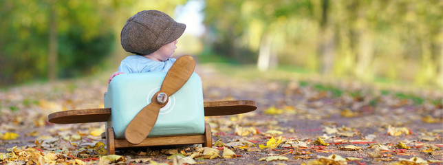 kleiner Junge im Holzflieger im Herbst