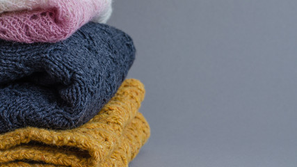 Pile of knitted winter clothes on gray background