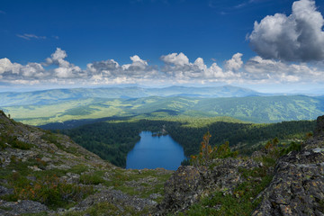 view from the top of the mountain to the blue lake surrounded by coniferous forest and mountain range