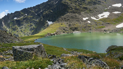 blue alpine lake formed from a glacier on top of a mountain