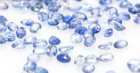 Many blue sapphire stones on a white background. Brilliant gemstones.