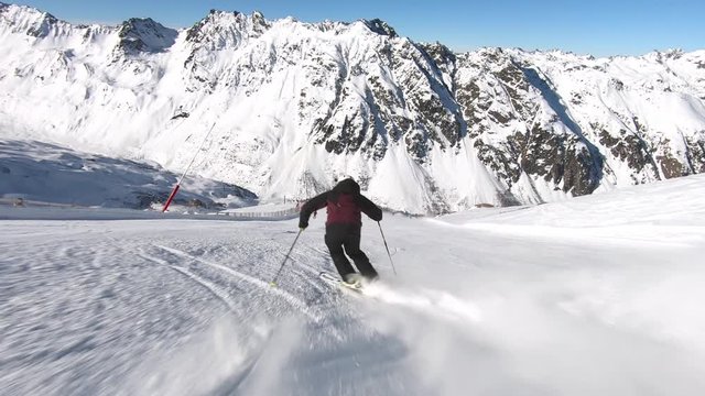 Professional skier racing down a steep ski slope in rythmic short turns. Great mountain view with a lot of ski action. Carving slalom turns. Very smooth and steady filming. Slomotion sixty frames /s.
