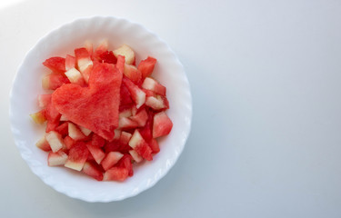 Watermelon heart and pieces of watermelon in a white plate on a white background