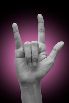 Female's hand doing sign language "I love you". isolated on gradient background.  Metal sign. Communication concept.