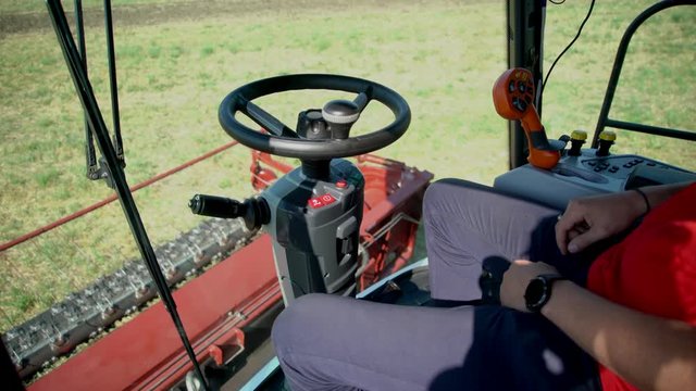Unmanned autonomous harvester on the field. View from the cockpit. The driver does not keep his hands on the steering wheel