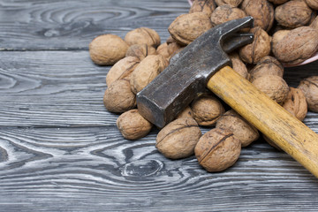 An overturned basket of walnuts. There is a hammer nearby. Against a background of painted pine boards.