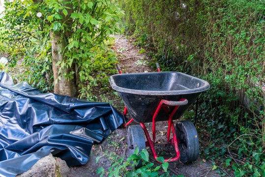 Wheelbarrow And Pond Liner In A Garden