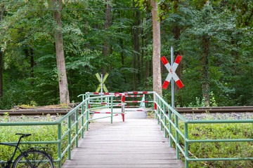 railroad  crossing in a forest for pedestrians with andreas cross and bars for protection