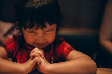 Asian little girl hand praying for faith, spirituality and religion.
