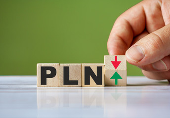 Word PLN currency symbol concept and hand turn wooden block and change red arrow to green or vice versa