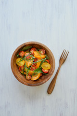 fresh and healthy tomato salad in wooden bowl standing on the white background