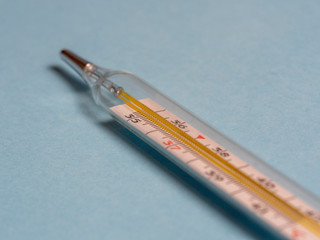 mercury thermometer on a blue background, close up, selective focus. Tool for changing the...