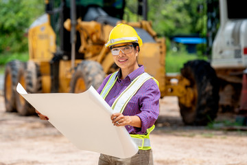 Female engineer worker on construction site outdoors with excavator in background,construction...