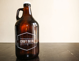 big orange glass bottle with handle for craft beer on a wooden rural table and white background