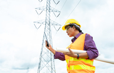 Electrical engineer use tablet working check high voltage pole Power Transmission.