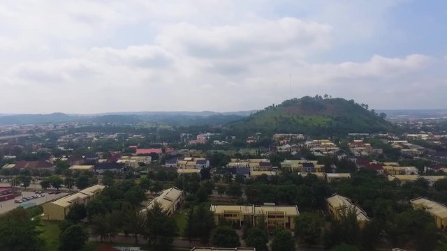 Drone zooms out over houses surrounding hill reaches a construction site