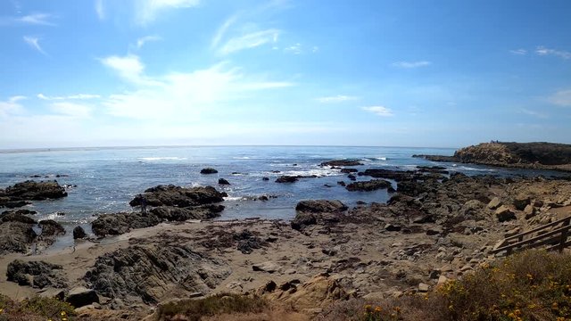 Coastal views of Moonstone Beach in San Luis Obispo, California (USA). Slow motion panoramic panning to the right showing a staircase that leads down to the beach and ocean tide pools.