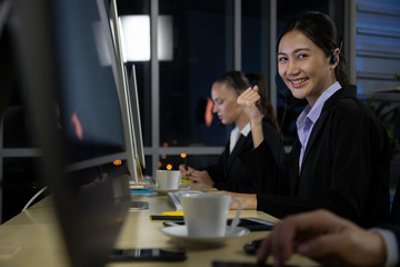 Group of Young call center staff talking and provide services to customers via headphones and microphone cable. Professionals with speech, service mind and information recording skills. Night mode.