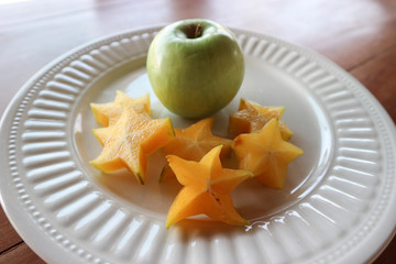 White plate with carambola and fresh apple.
