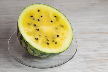 yellow watermelon half on a white wooden table