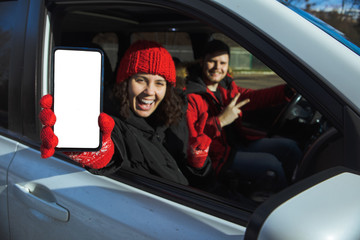 couple sitting in rent car woman holding phone with white empty screen