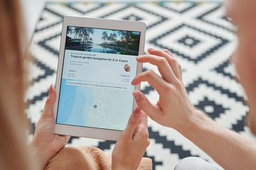 Hands of young man over touchscreen held by his wife scrolling through websites