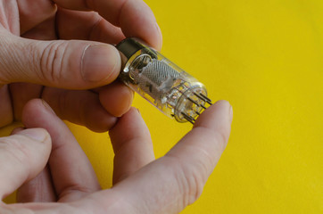 Male hand holds a vacuum tube on a yellow background.