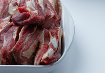 Beef ribs in a white, glass dish. Ingredient, fresh meat to cook. Veins, beef ribs, meat texture. Increase in prices for natural, farm products, imports. Meat on a plate