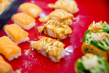 Salmon spicy sushi put on red wood, in focus selective.